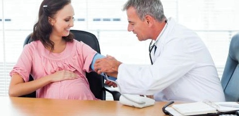 Ein Arzt misst den Blutdruck einer Schwangeren