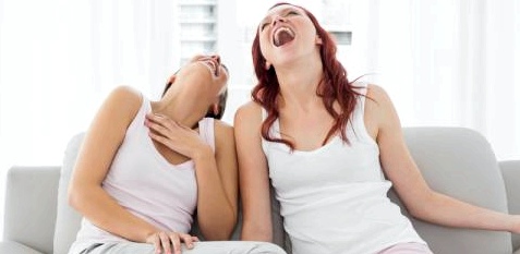Frauen sitzen lachend auf dem Sofa