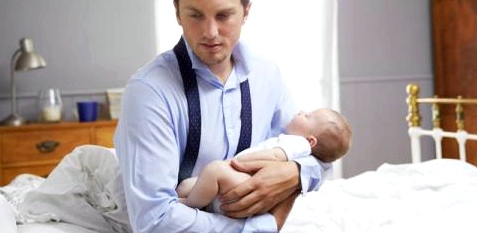 Ein Vater hält sein Baby im Arm und schaut nachdenklich